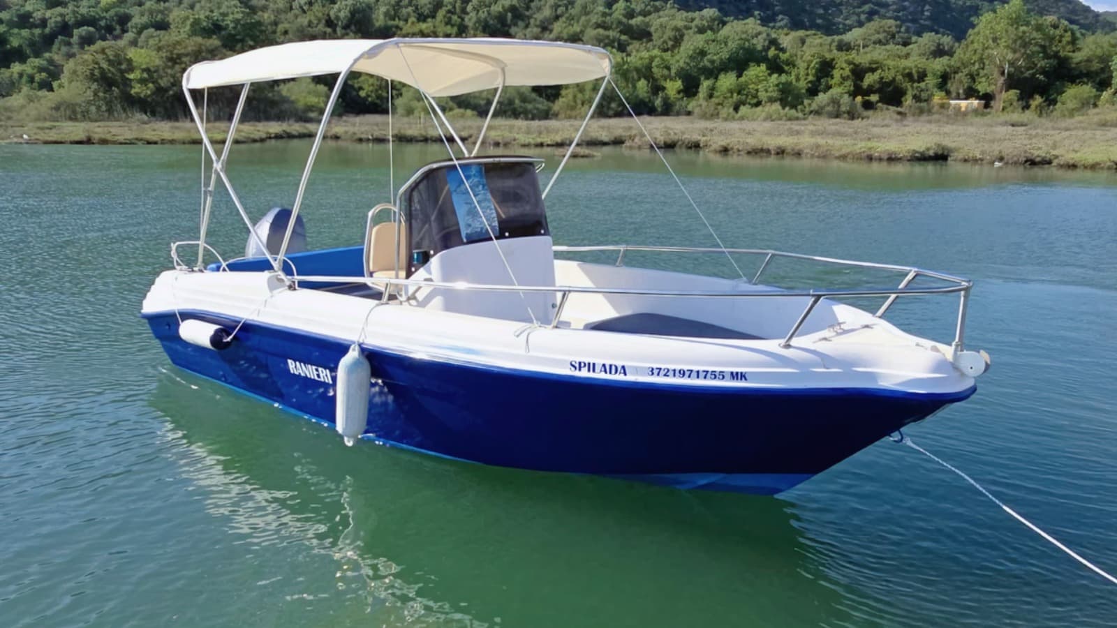 Side profile of the Spilada self-drive rental boat moored near Ksamil, showing the full Bimini top and official boat registration