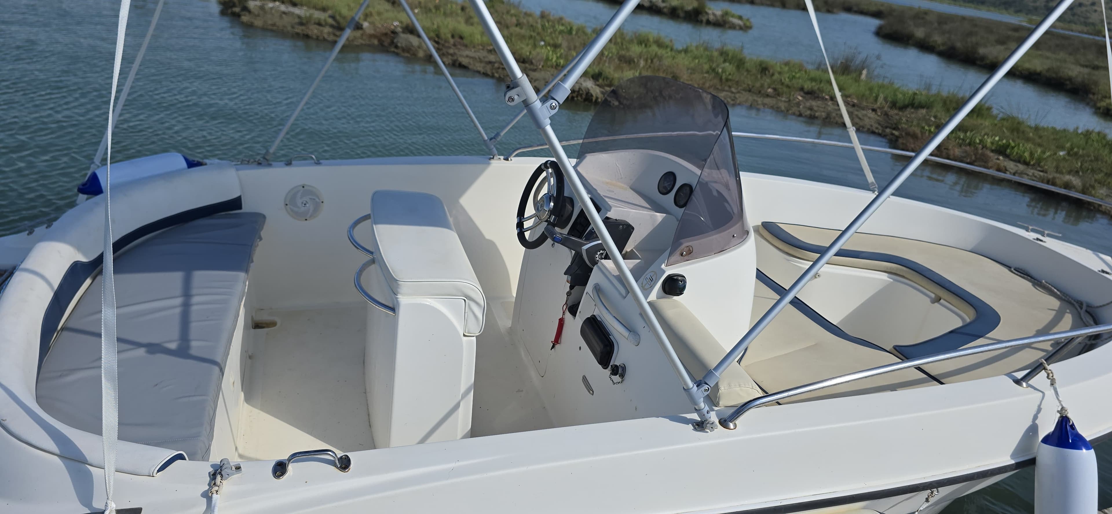 Wide interior layout of the Max 2 rental boat showing ample deck space, rear bench seating, and the steering console for up to 5 passengers