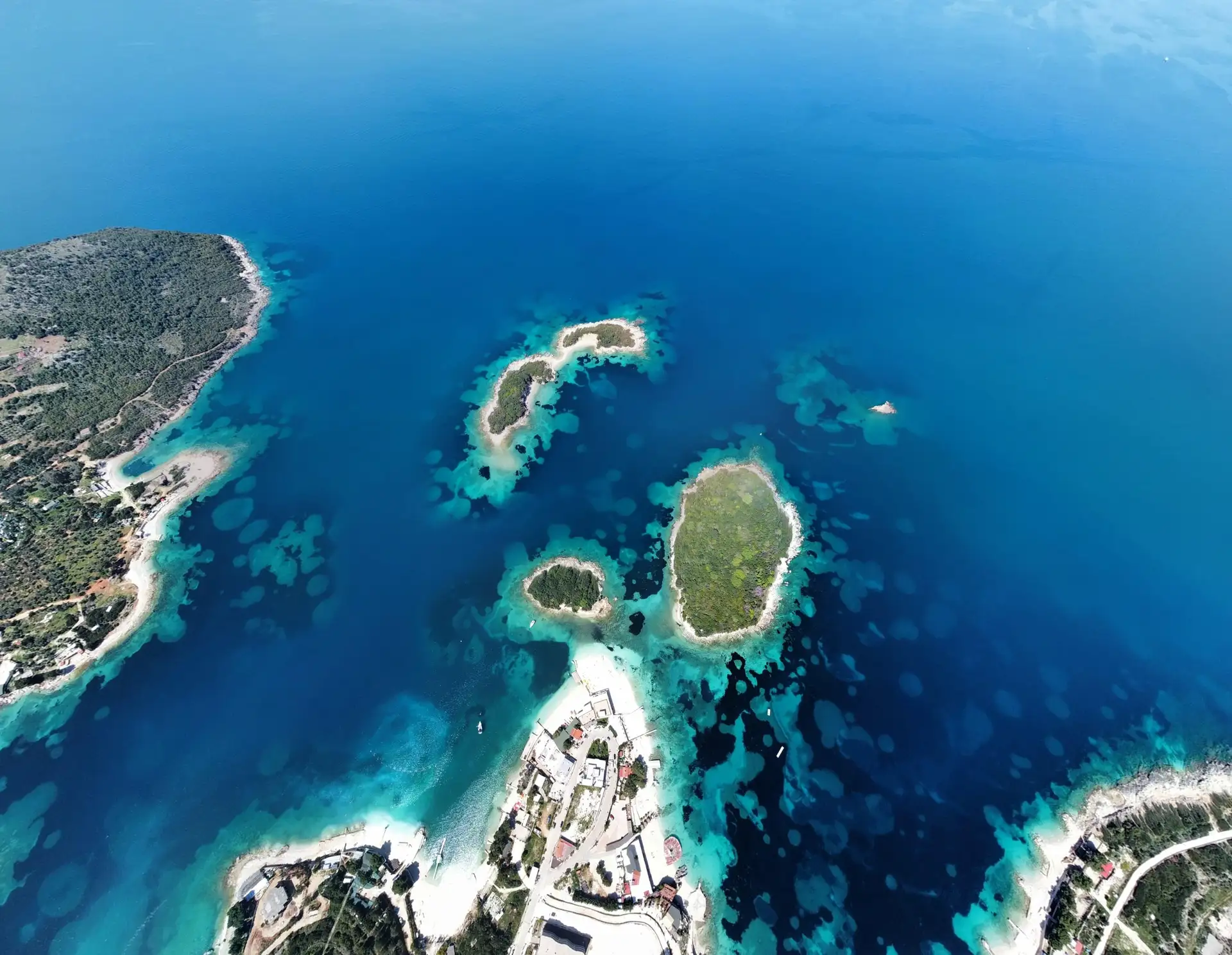 Panoramic drone view of the lush, green Five Islands of Ksamil surrounded by turquoise waters of the Ionian Sea in Albania